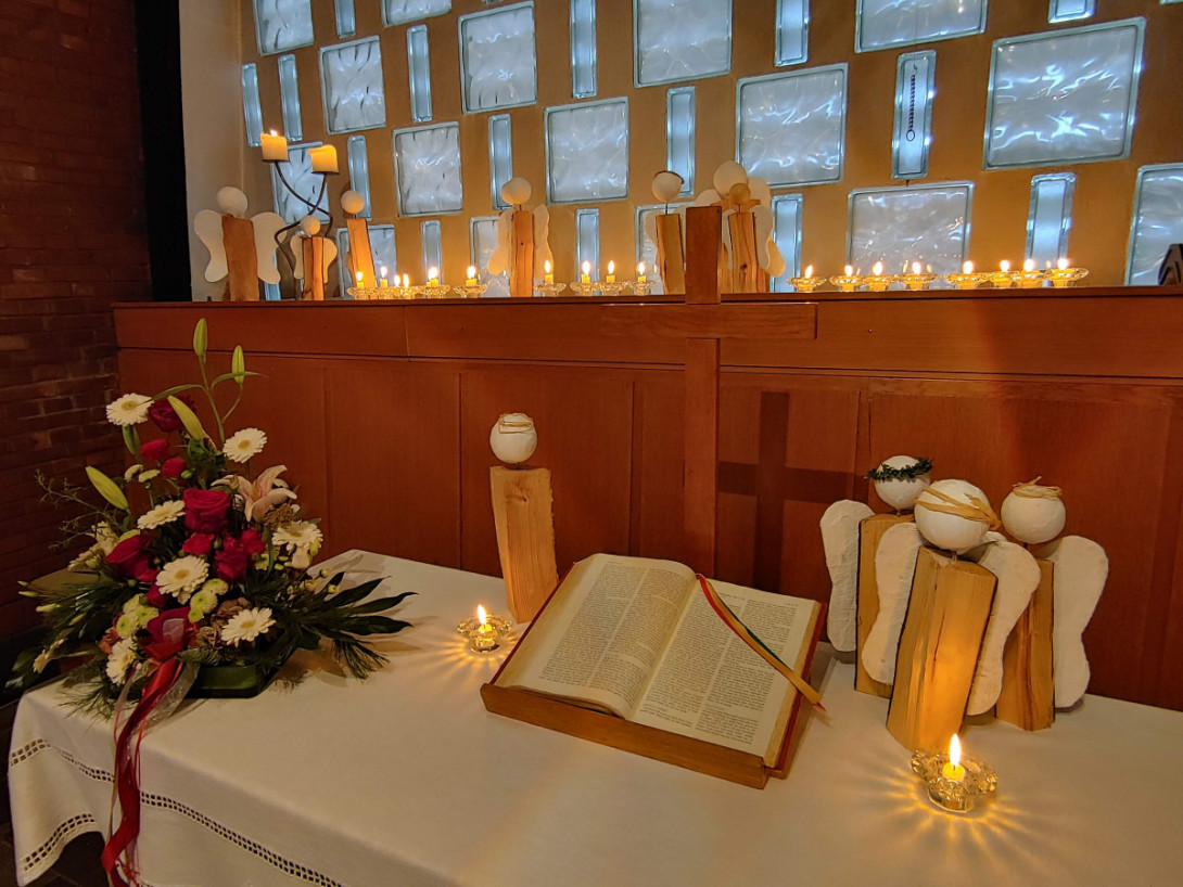 Bibel, Blumen, viele Kerzen und viele Engel auf dem Altar und dahinter