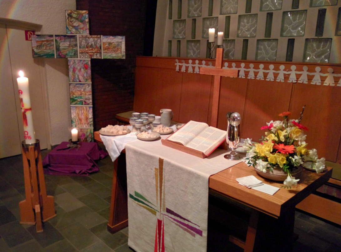 Altarraum mit gedecktem Abendmahlstisch und Osterkerze zu Ostern.