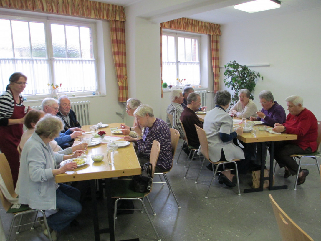 Senioren sitzen an Tischen und essen