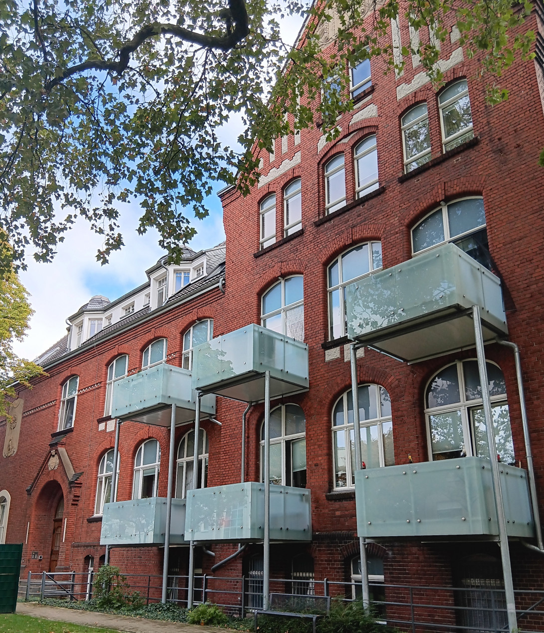 Tagespflegeeinrichtung „Alte Cecilienschule“. Ein 3-stöckiger Altbau aus roten Backsteinen und mit weißen Vorbau-Balkonen.