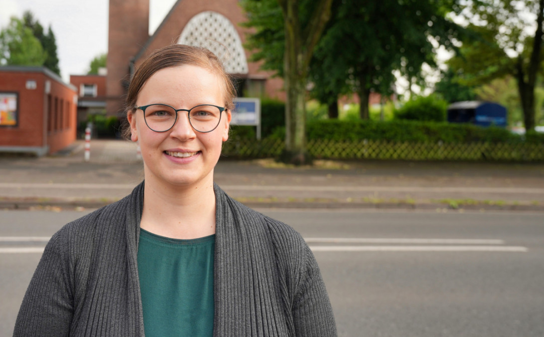 Porträt der Pfarrerin Laura Bowinkelmann vor der Evangelischen Kirche Scherpenberg