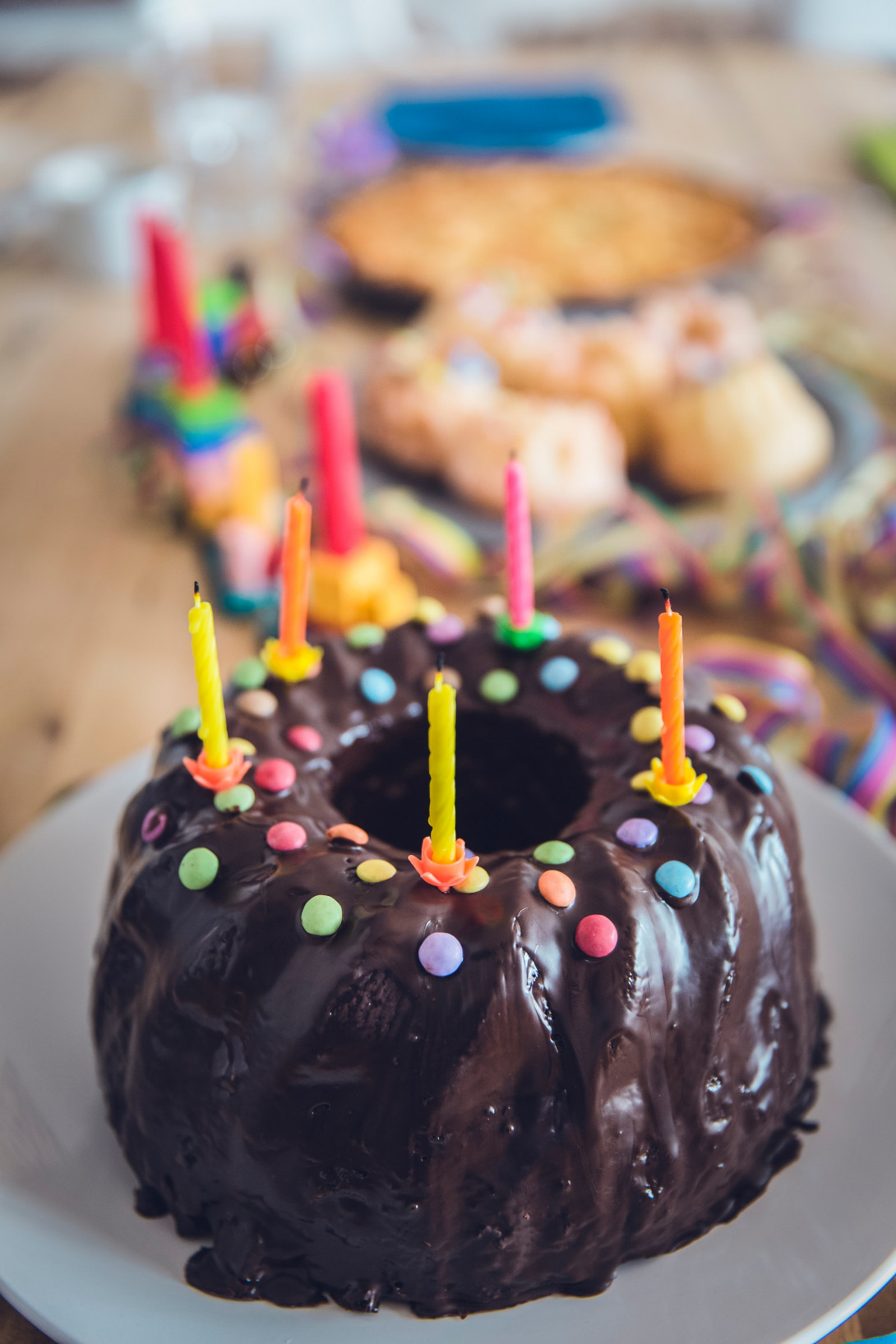 runder Kuchen mit Schokoglasur, Schokoperlen und kleinen bunten Kerzen