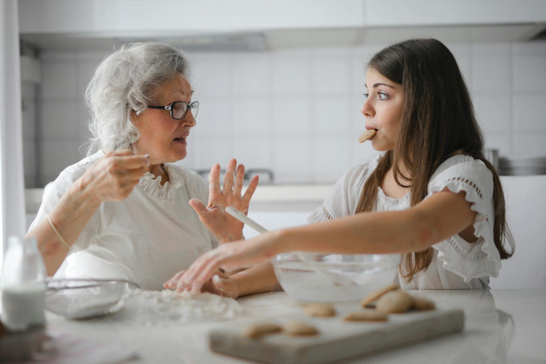 Nachdenkliche Großmutter Mit Enkelin, Die Interessante Unterhaltung Beim Gemeinsamen Kochen In Der Leichten Modernen Küche Hat