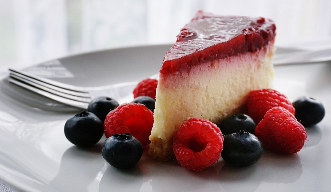 Ein Stück Fruchttorte mit Waldbeeren auf einem Teller.