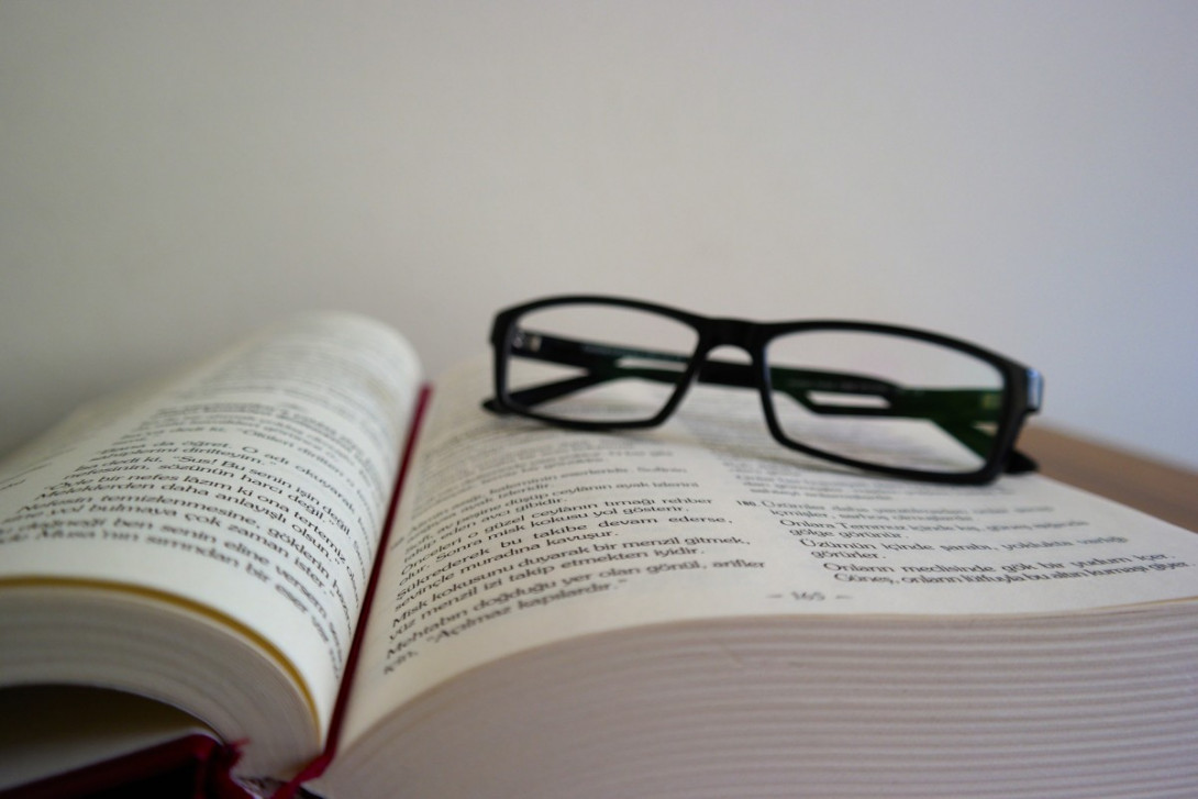 eine Brille liegt auf einem aufgeschlagenem Buch