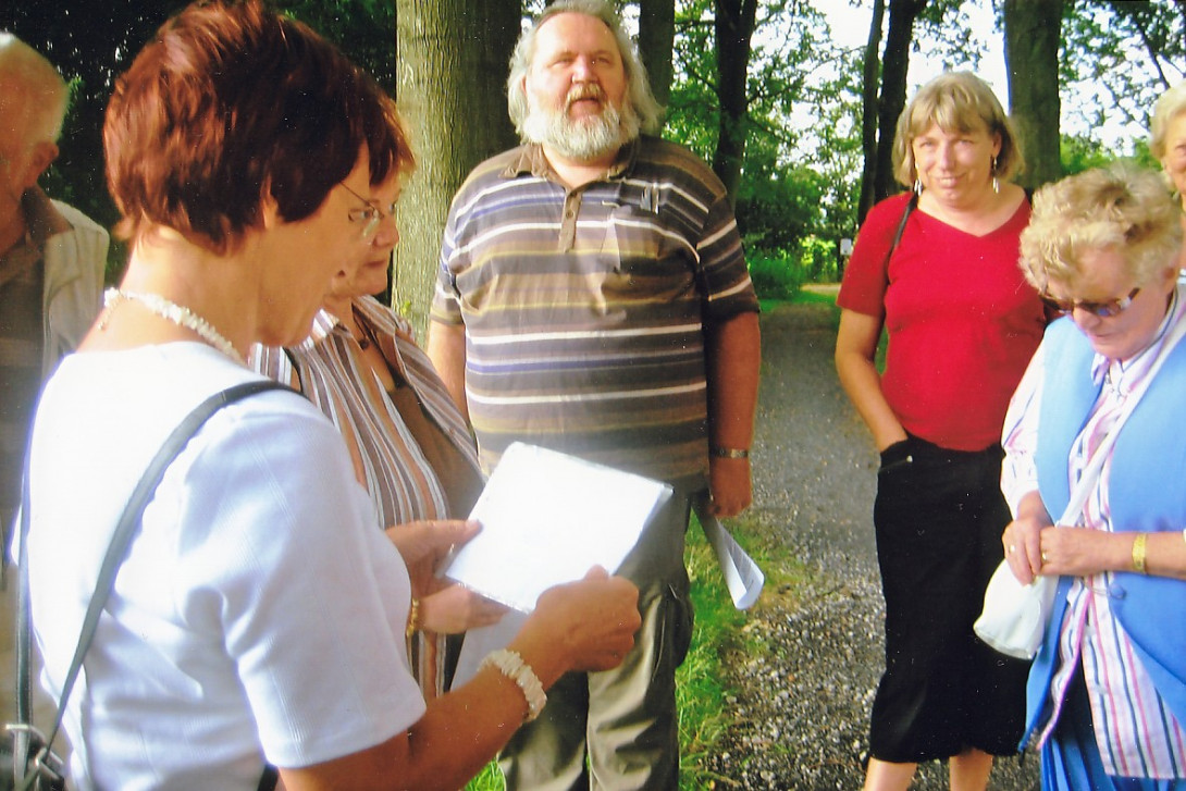 Erwachsene im Wald. Eine Frau schaut auf ein Blatt Papier.